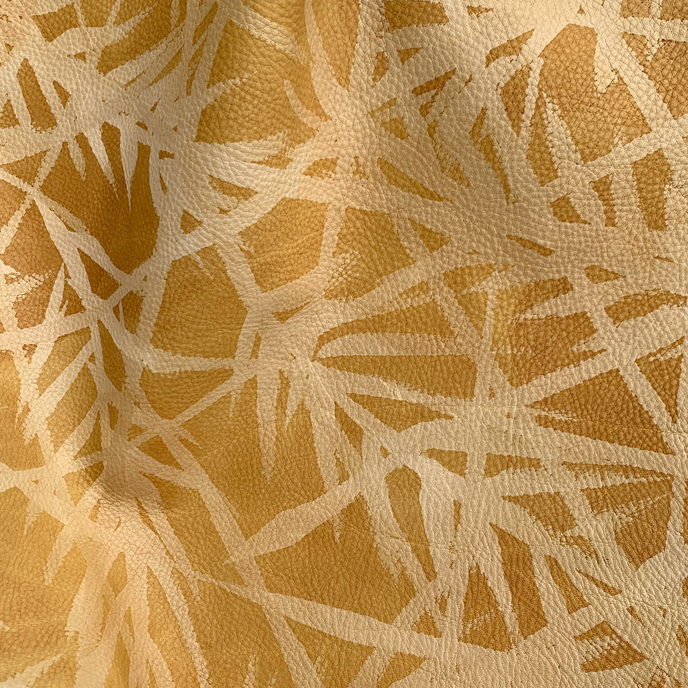 Close-up of a cowhide rug in orange with a painterly botanical overlay in yellow.