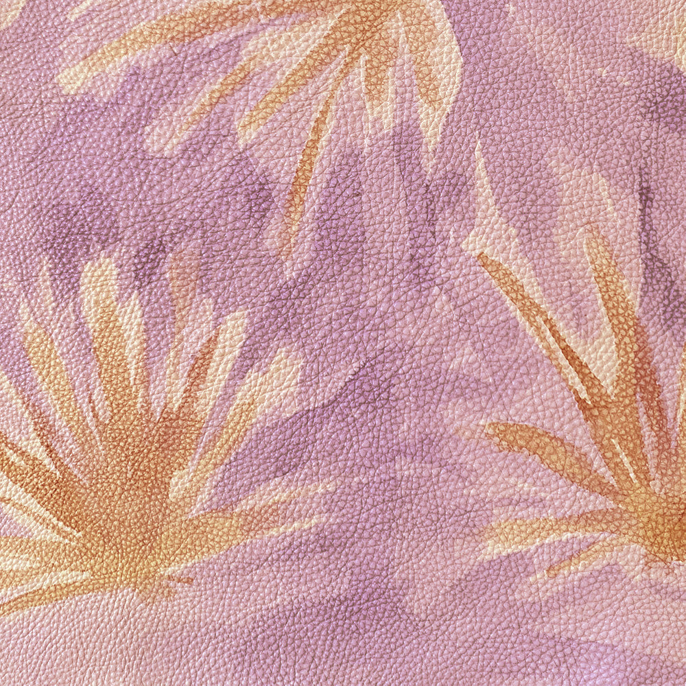 Close-up of upholstery leather in purple with a painterly flower print in yellow and orange.