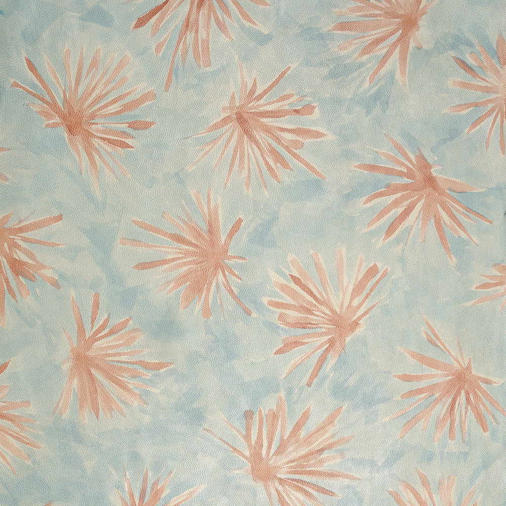 Close-up of upholstery leather in light blue with a painterly flower print in yellow and coral.