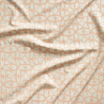 Close up of gently draped fabric with large scale geometric lattice design in cream and light pink. 
