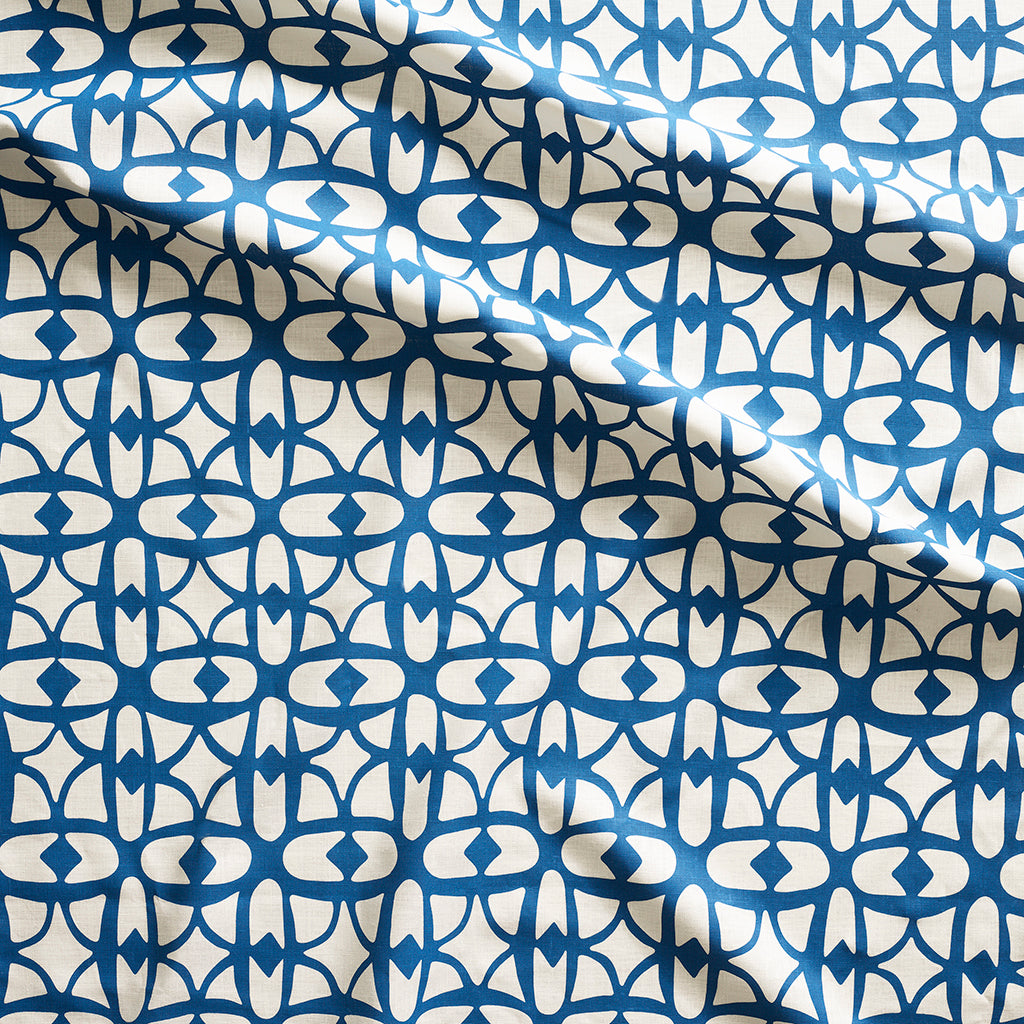 Close up of gently draped fabric with large scale geometric lattice design in white and blue.