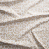 Close up of gently draped fabric with large scale geometric lattice design in white and ecru.