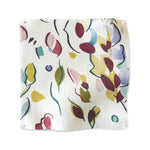 Square fabric swatch in a painterly leaf print in shades of purple, blue and green on a white field.