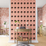 A maximalist living space with an accent wall papered in a repeating palm tree print on a mottled white and coral field.