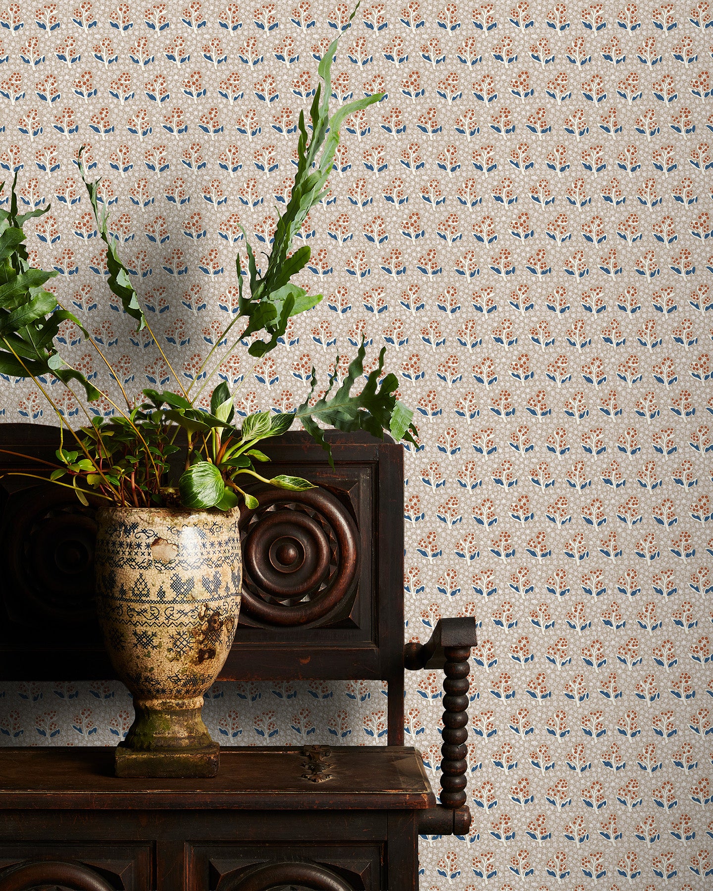 Decorative wallpaper with a subtle floral pattern, a vintage wooden chair, and a plant on a wooden surface.
