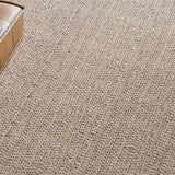 Wall to wall broadloom carpet in a textural taupe with a brown leather ottoman. 