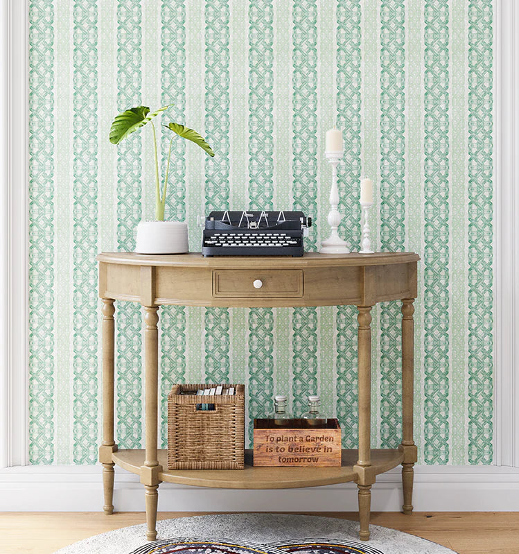 A styled end table stands in front of a wall papered in a geometric stripe print in green, turquoise and cream.