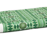 Partially unrolled fabric in a playful geometric stripe print in shades of green with purple accents.