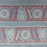 Block printed fabric in an ornamental paisley stripe in indigo and red on linen.