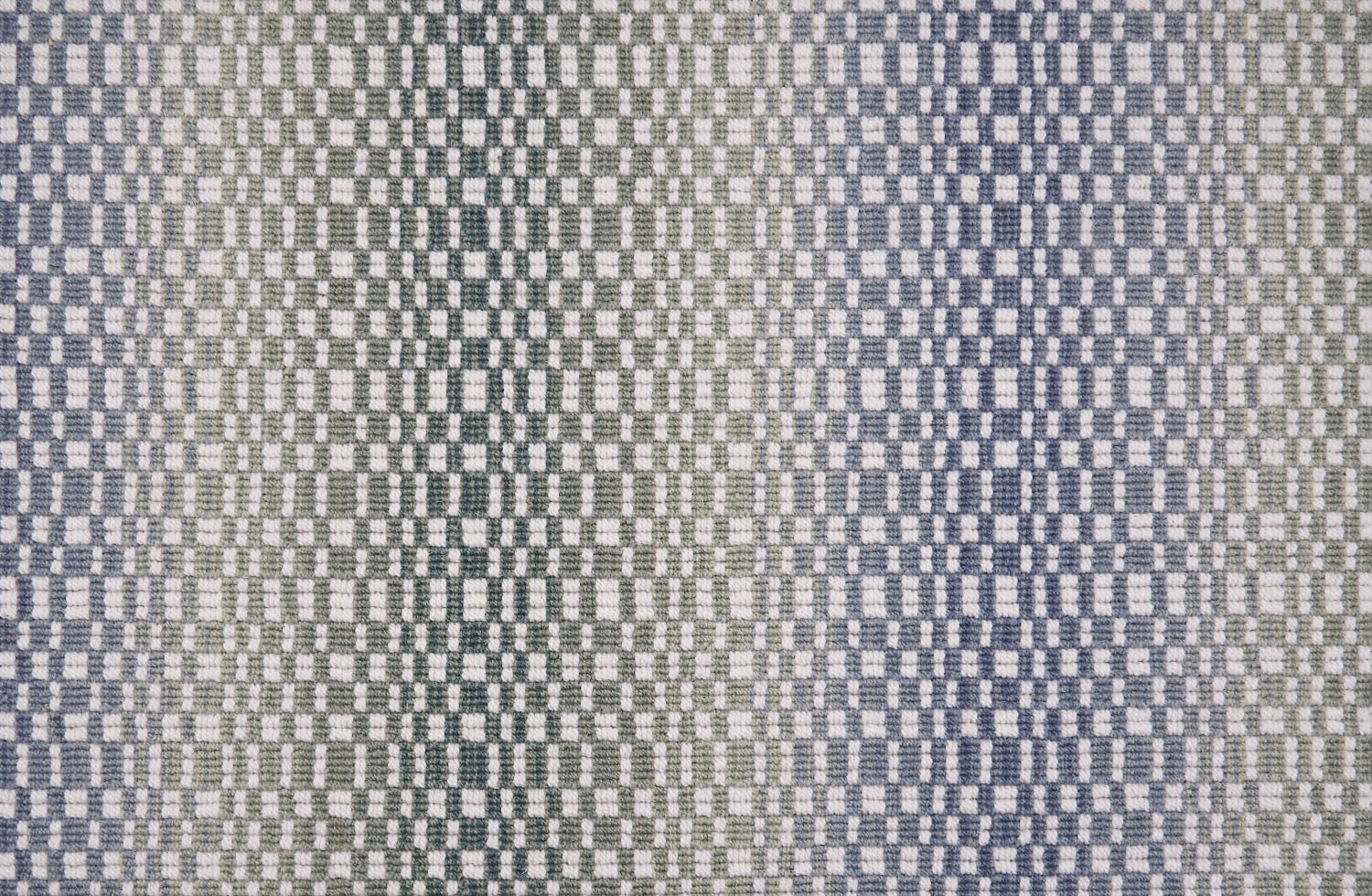 Broadloom carpet with a white checkerboard pattern with an ombré effect in blue and green. 