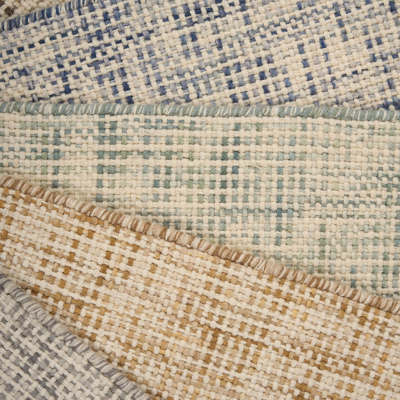 A pile of broadloom carpets in textural basket weaves in an array of colors. 