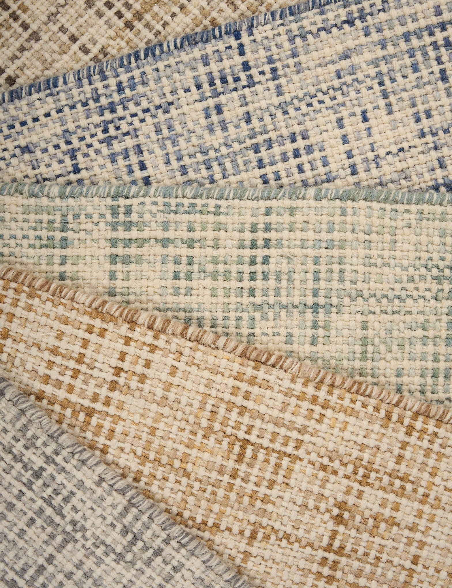 A pile of broadloom carpets in textural basket weaves in an array of colors. 