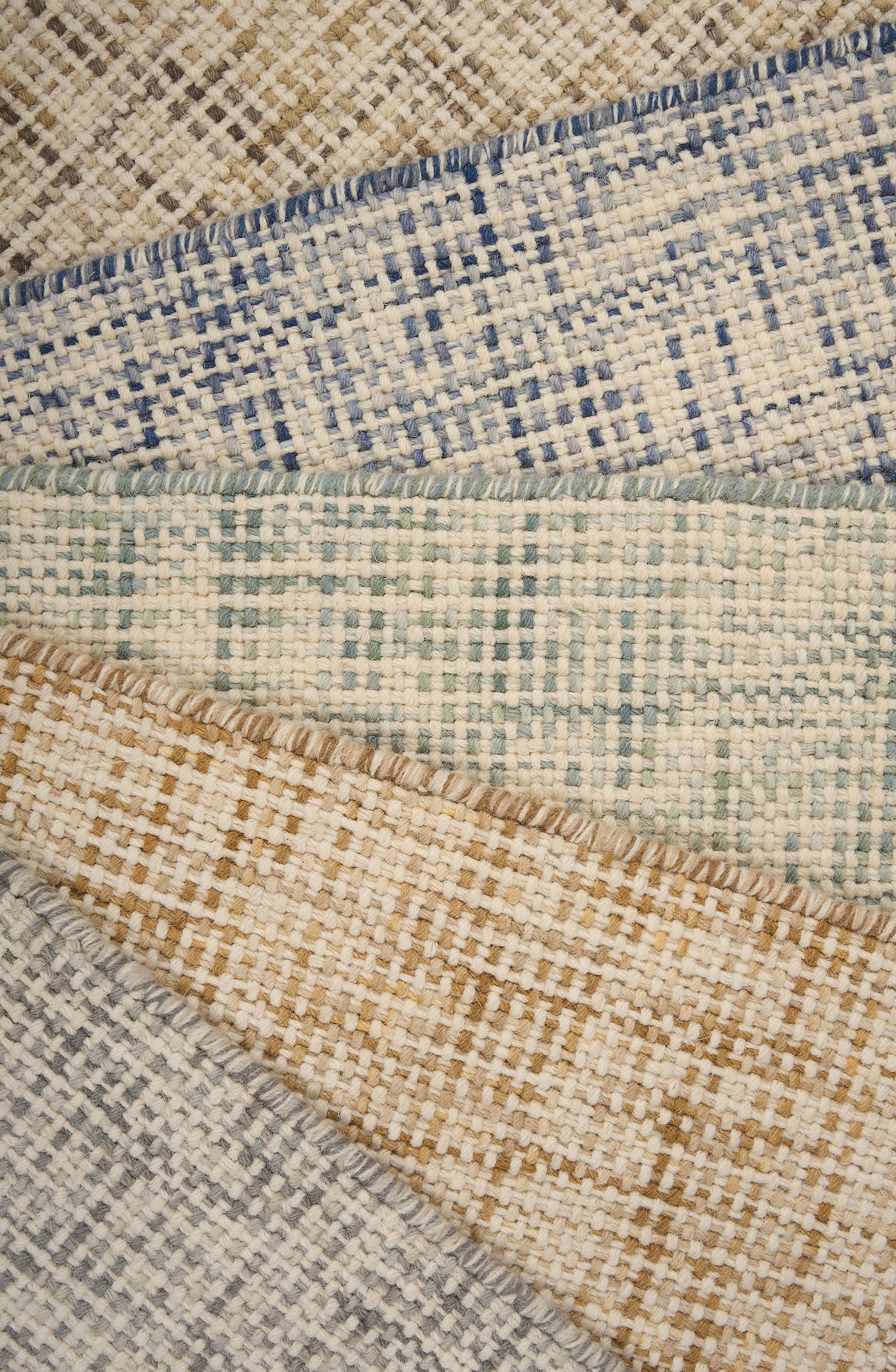 A pile of broadloom carpets in textural basket weaves in an array of colors. 