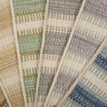 Broadloom carpet samples spread in an arc in a striped pattern in a range of colors. 