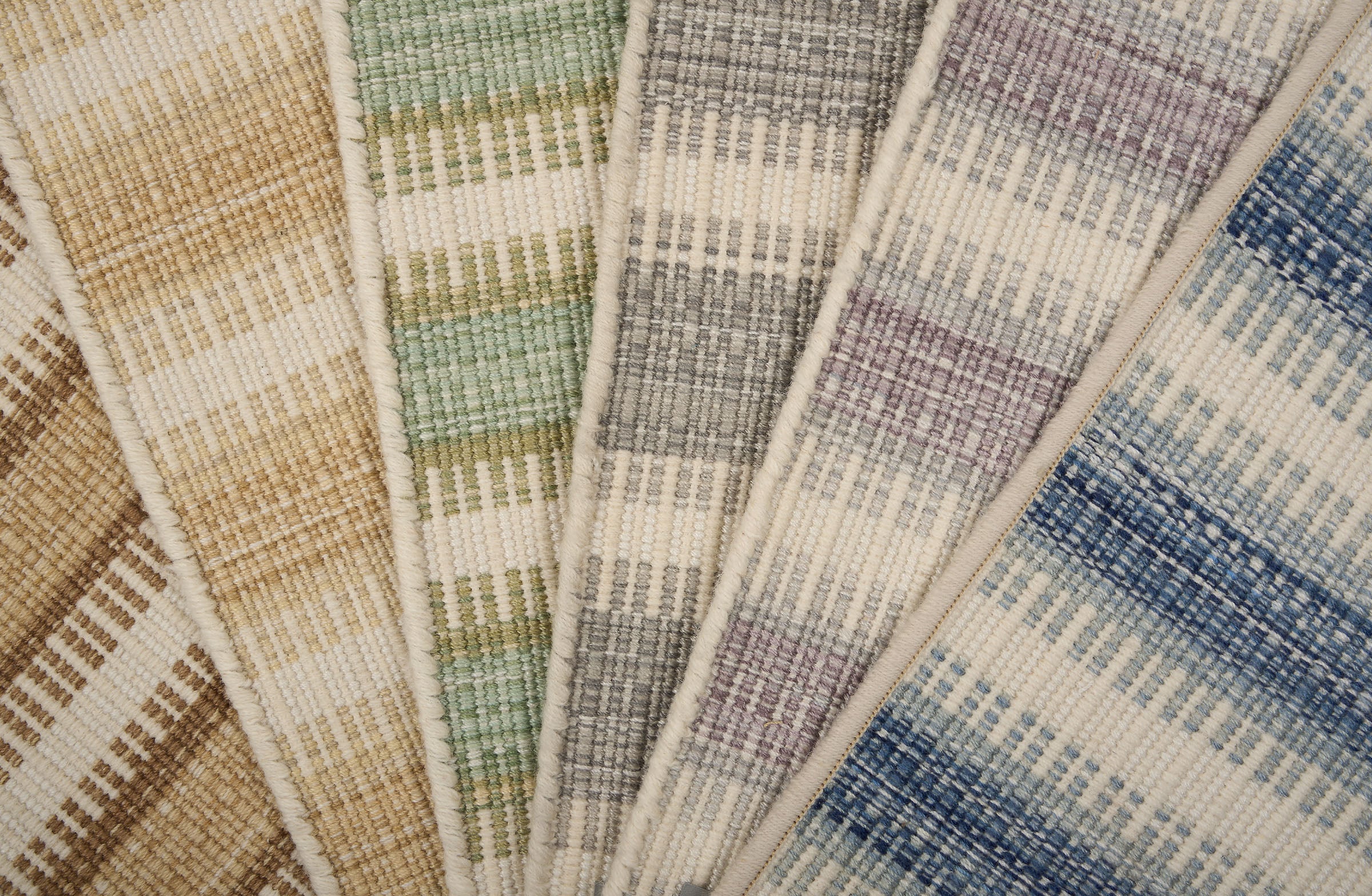 Broadloom carpet samples spread in an arc in a striped pattern in a range of colors. 