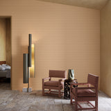 Modern interior with two brown chairs, a floor lamp, and a side table against a textured beige wall.
