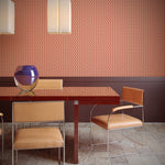 Dining area with a table and chairs against a patterned wall in orange.