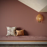 Patterned wall with a bench and decorative pillows in a room with a textured wall and light fixture.