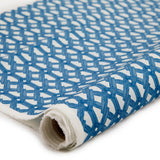 Partially unrolled fabric in an intricate lattice print in navy on a cream field.