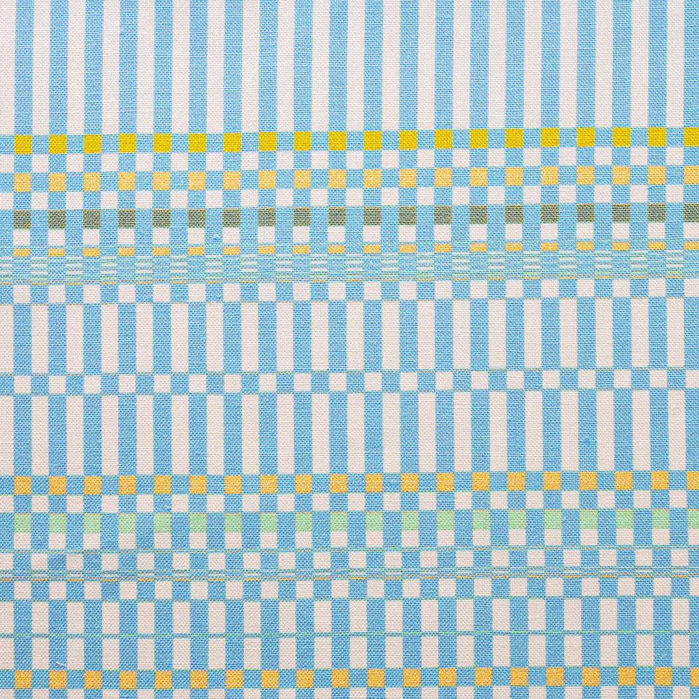 Detail of fabric in a dense irregular check print in light blue with yellow and green accents on a white field.
