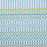 Detail of fabric in a dense irregular check print in light blue with yellow and green accents on a white field.