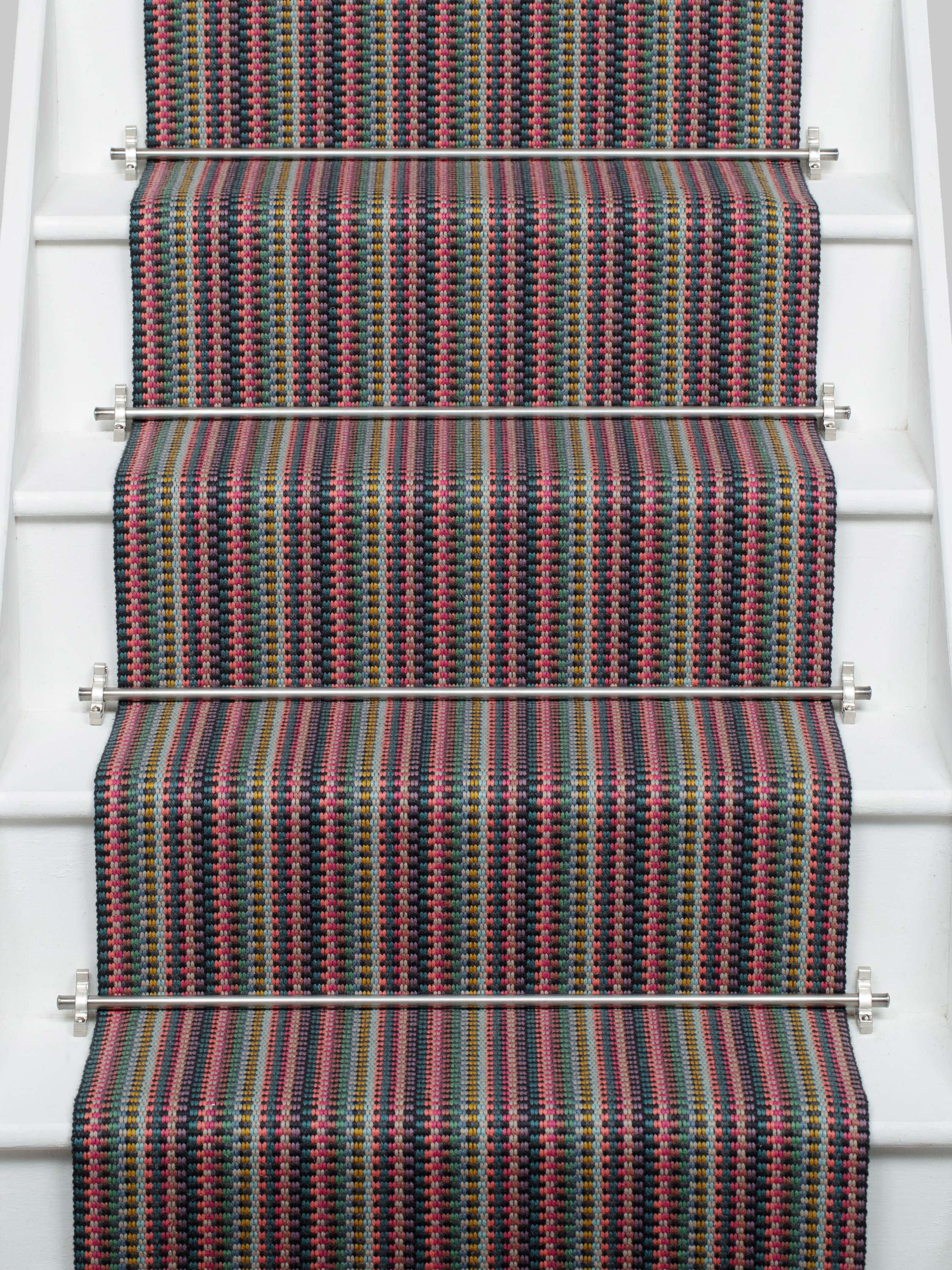 Striped flatweave runner in pink green purple blue with black border on white staircase