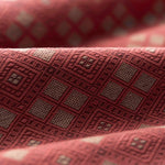 Close-up of textured fabric with a geometric pattern in shades of red.