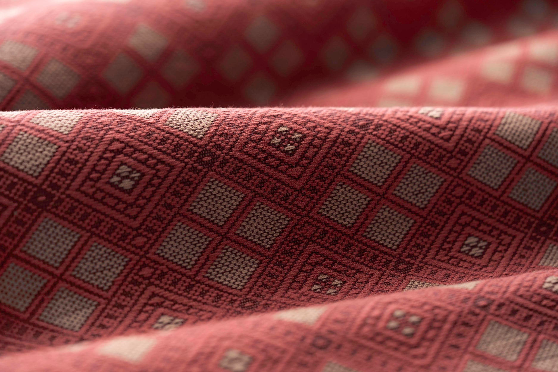 Close-up of textured fabric with a geometric pattern in shades of red.