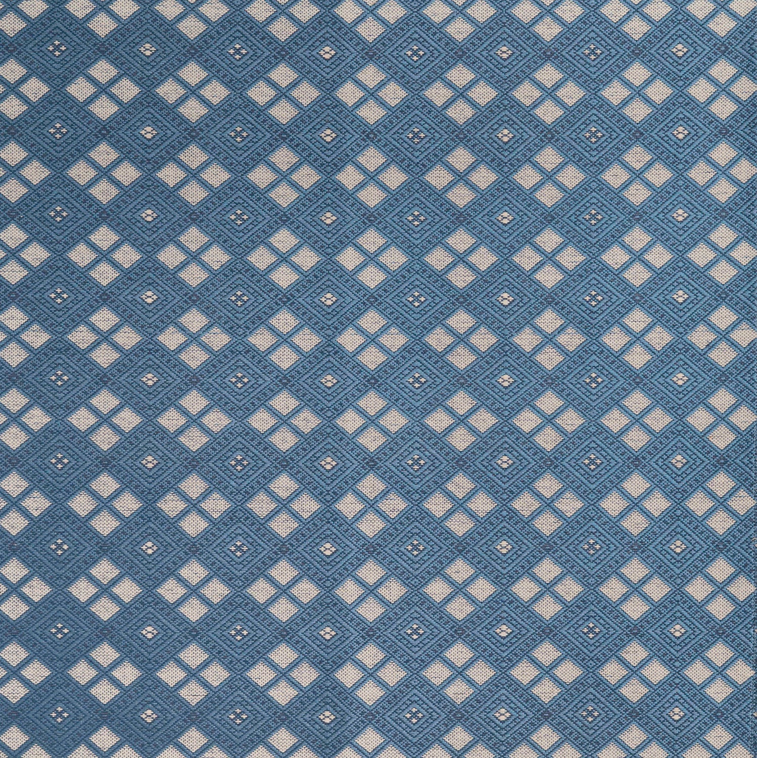 Woven fabric with ornate diamond design with cream accents on blue.
