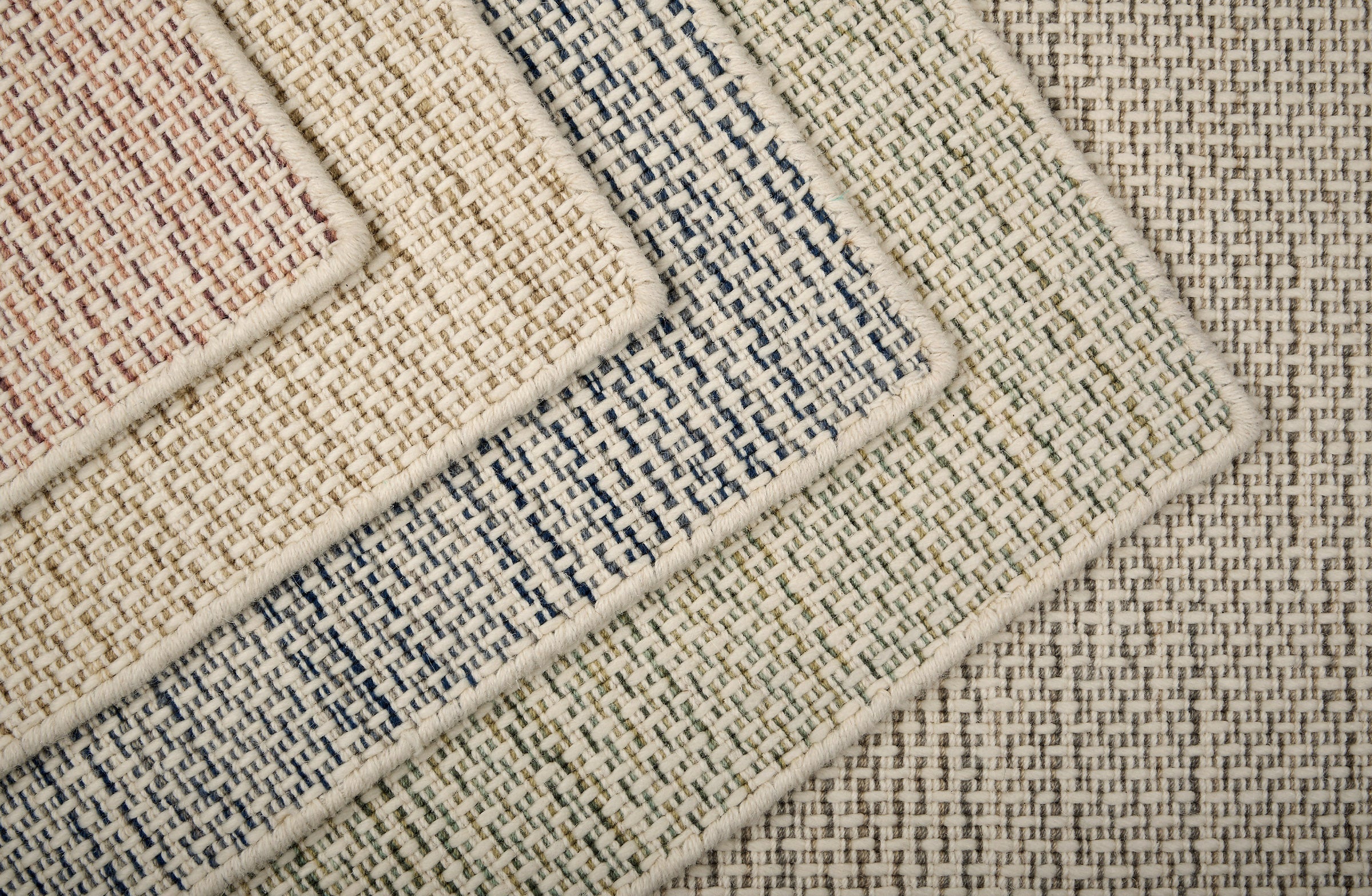 Close-up of various textured rugs with textural stripe patterns in five colors. 