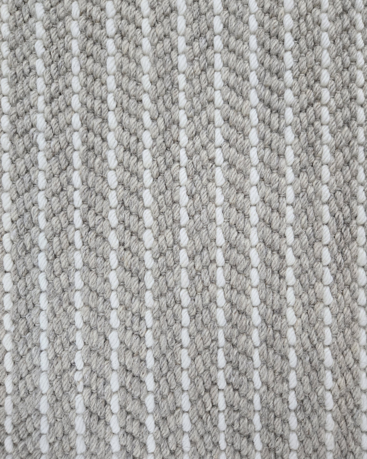 Close-up of a broadloom carpet with vertical stripes in grey and white.