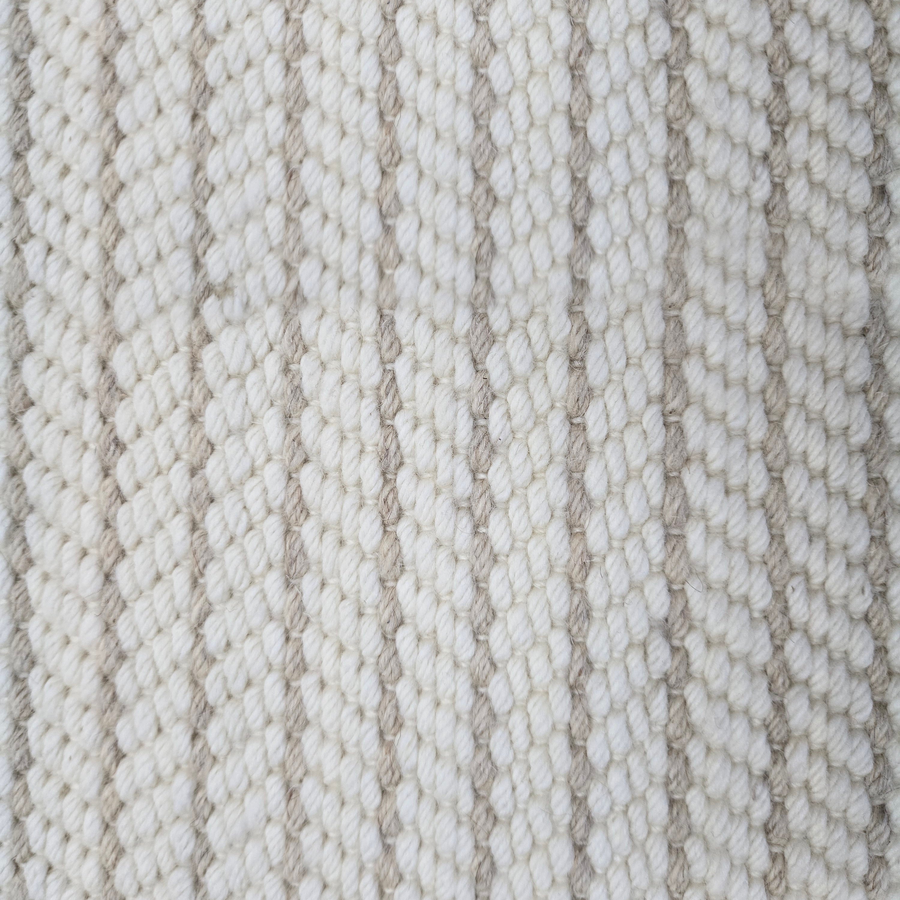 Close-up of a broadloom carpet with vertical stripes in beige and tan