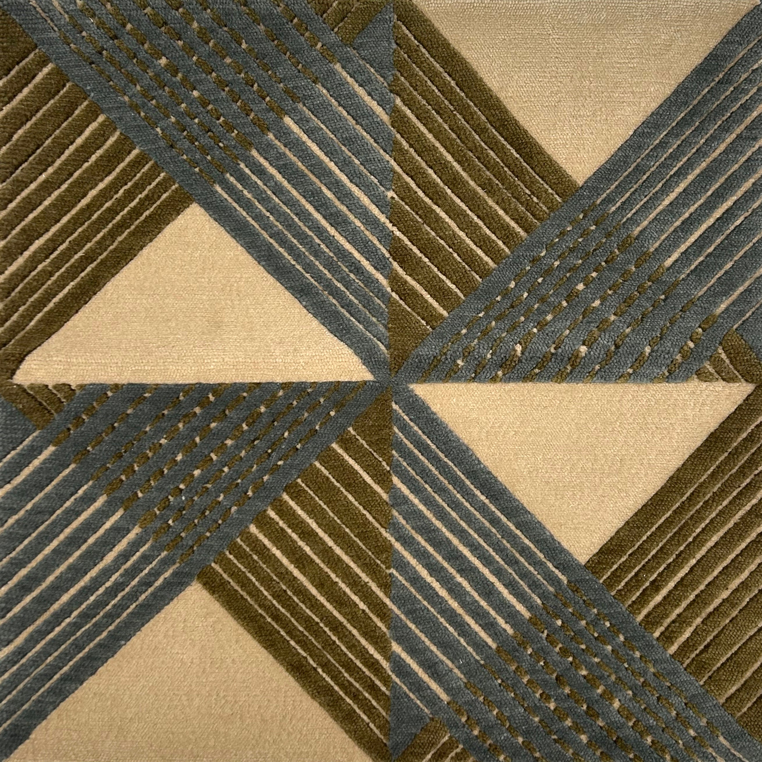 Close-up of a geometric patterned rug with triangles and stripes in green and blue.