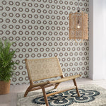 Styled living room tableau with a wall papered in an intricate circular print in shades of green, red and gray.