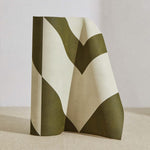 A curved partition stands on the ground, covered in a large-scale geometric print in olive on a cream field.