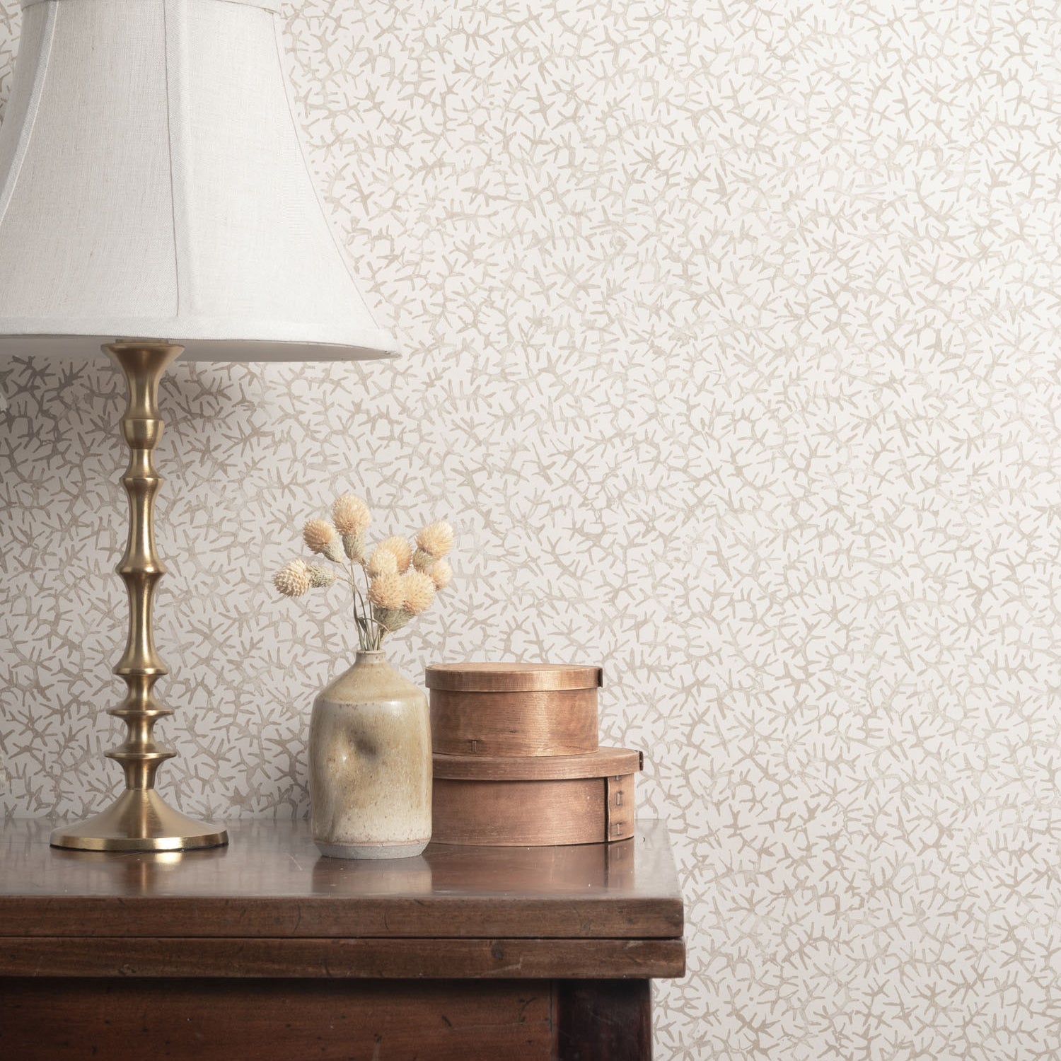 Vignette with brass table and props against a gray watercolor coral wallpaper. 