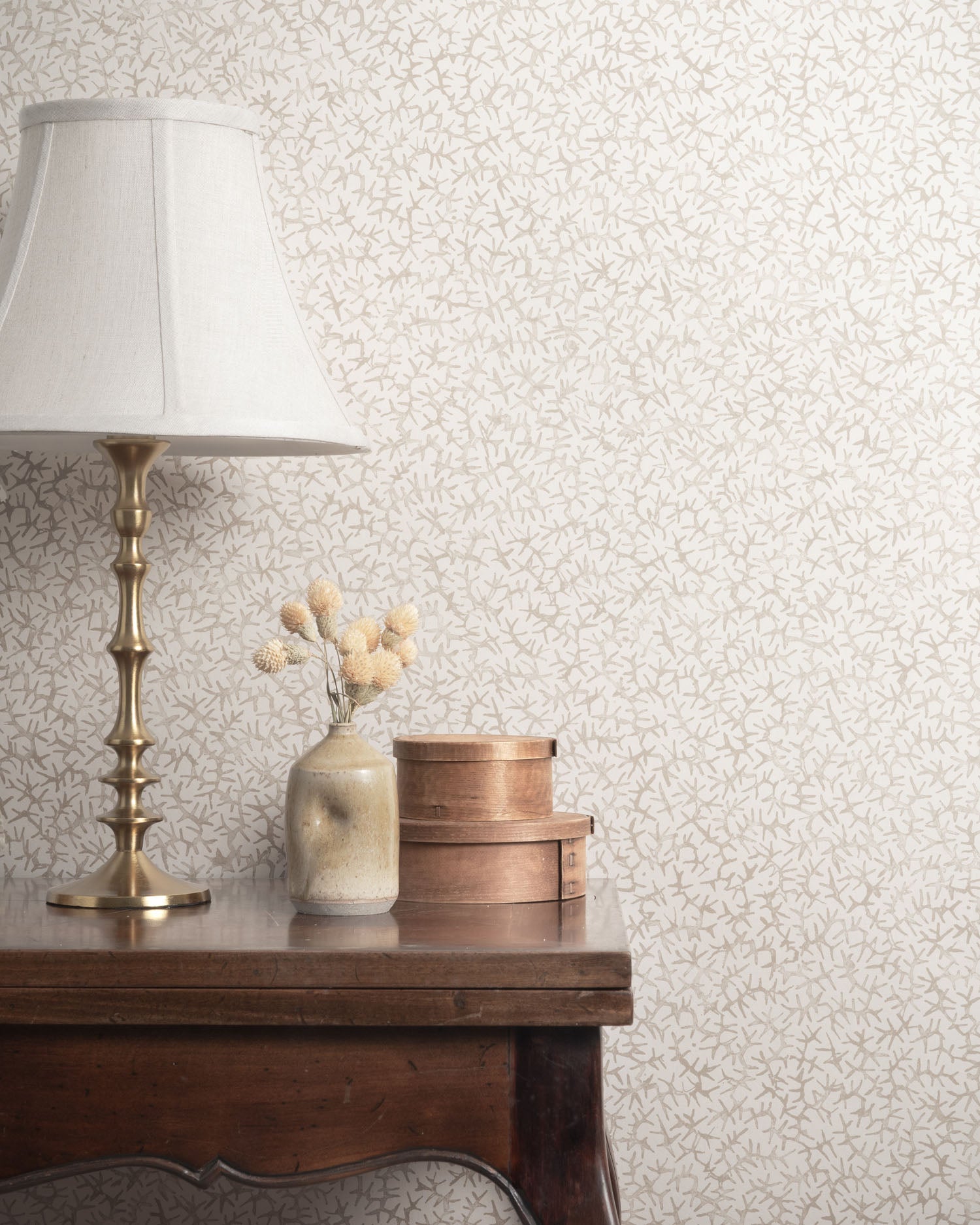 Vignette with brass table and props against a gray watercolor coral wallpaper. 