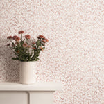 Mantle with flower vase against watercolor coral wallpaper. 
