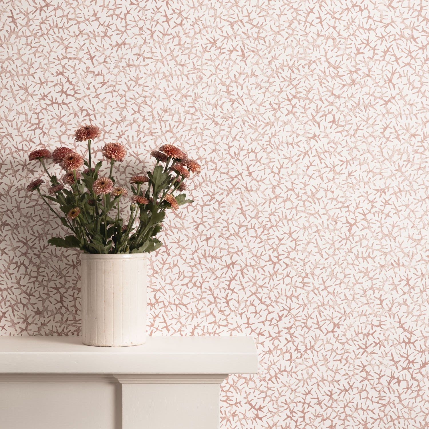 Mantle with flower vase against watercolor coral wallpaper. 