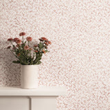 Mantle with flower vase against watercolor coral wallpaper. 