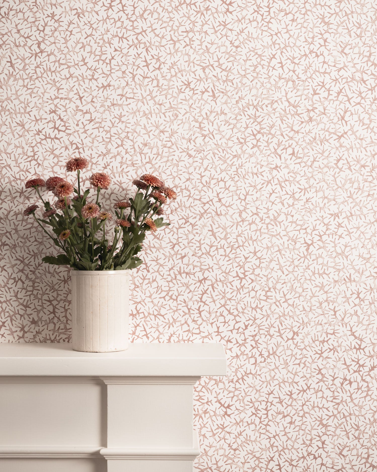 Mantle with flower vase against watercolor coral wallpaper. 