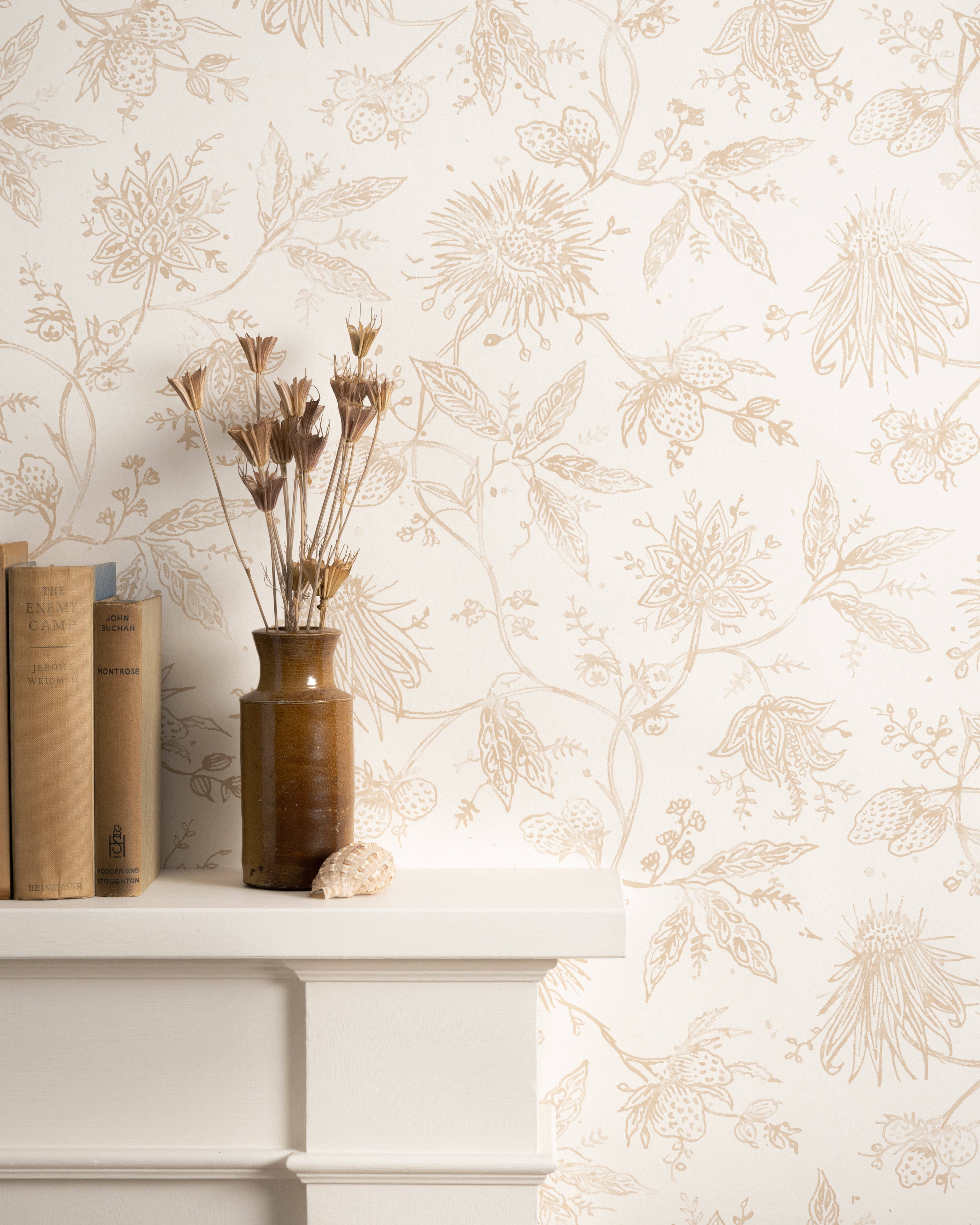 Mantle with books and flower vase against watercolor floral wallpaper. 