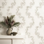 Mantle with vase against wallpaper with stylized leaf stripe. 