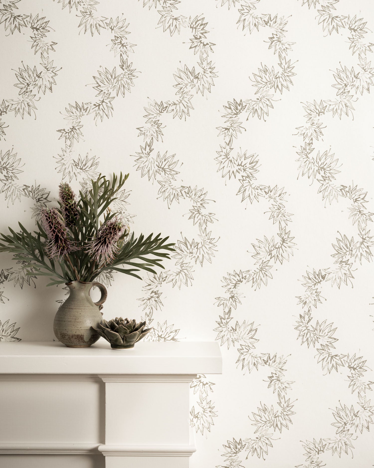 Mantle with vase against wallpaper with stylized leaf stripe. 