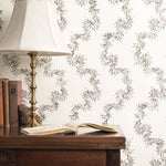 Wooden desk with lamp and books against decorative wallpaper with floral pattern.