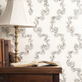 Wooden desk with lamp and books against decorative wallpaper with floral pattern.