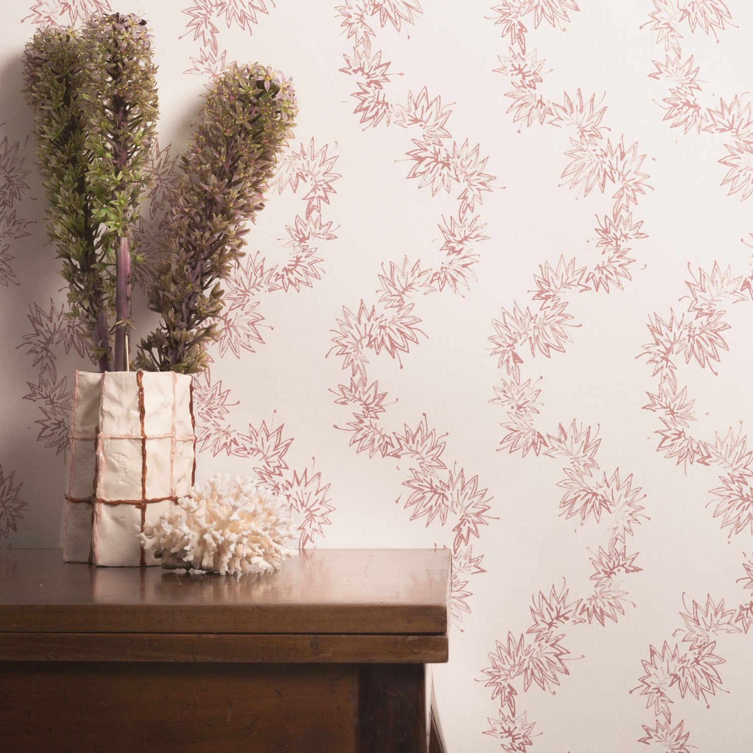 Decorative wallpaper with floral pattern and a wooden table with plants.