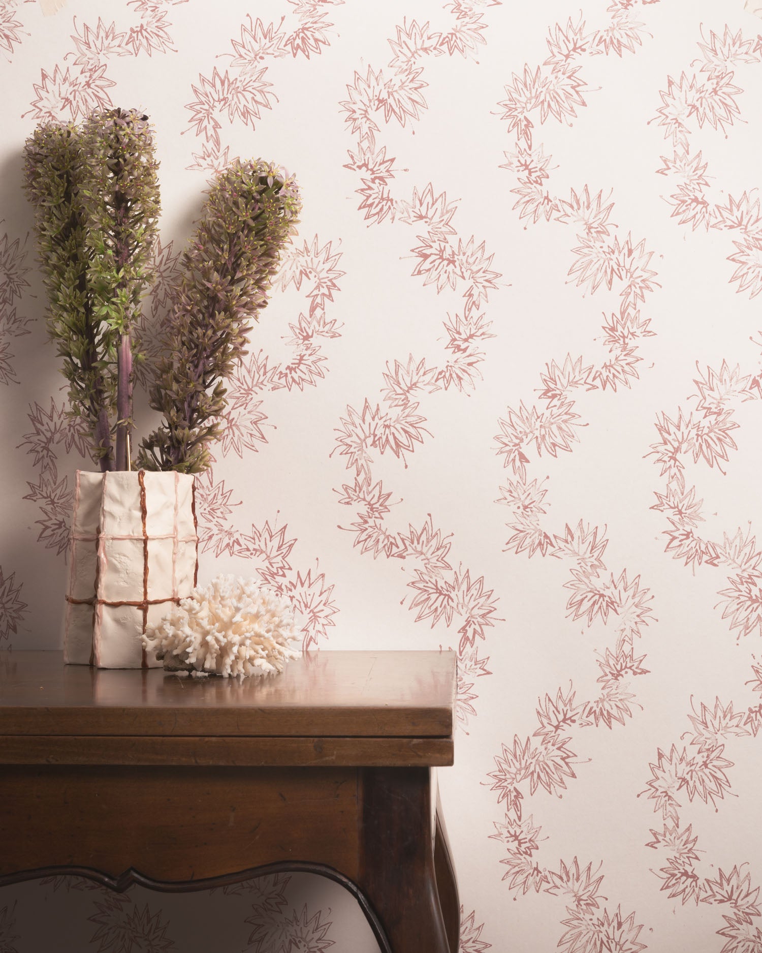 Decorative wallpaper with floral pattern and a wooden table with plants.