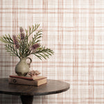 Vase with flowers and books on a table against a plaid wallpaper.