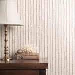 Decorative wallpaper with a subtle pattern, a lamp, and books on a wooden surface.